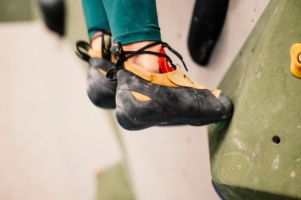 Un grimpeur porte des chaussons d’escalade au pied d’une paroi rocheuse.