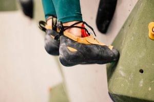 Un grimpeur porte des chaussons d’escalade au pied d’une paroi rocheuse.