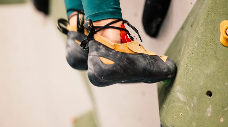 Un grimpeur porte des chaussons d’escalade au pied d’une paroi rocheuse.